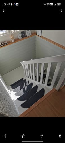 Anmelders trapp før renovering, som viser hvite trinn med mørke teppematter.