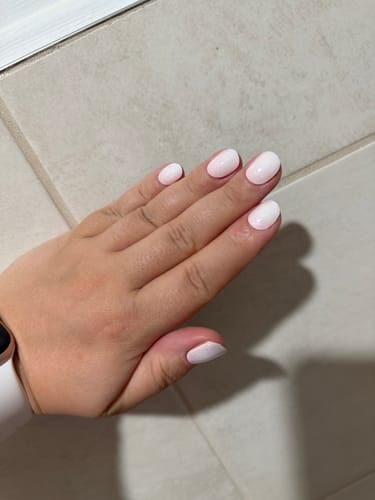 Hand einer Kundin mit aufgetragenen Blush Aurora UV-Nagelfolien mit einem hellen, dezenten Farbverlauf.