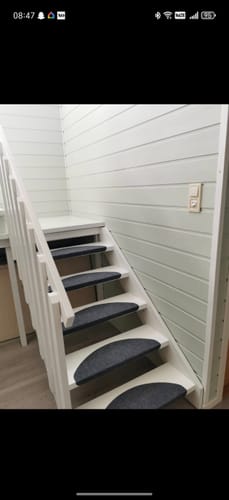 Kundens trapp sett nedenfra før renovering, med hvite trinn og rekkverk.