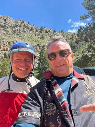 Customer wearing the El Jefe Azteca Guayabera outdoors with another person after kayaking, showing the patterned shirt worn open.