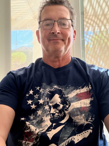 Reviewer wearing the navy Lincoln Flag T-Shirt, which shows Abraham Lincoln with a guitar and an American flag.