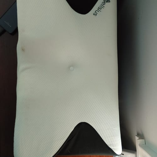 Un client montre son oreiller Papillon Cervical Cellsius blanc vu de dessus, posé sur une surface sombre.