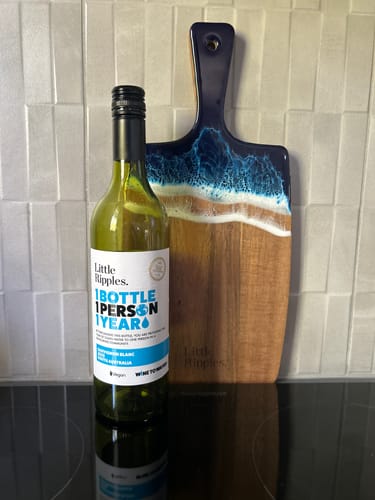 Customer's bottle of Sauvignon Blanc next to a wooden charcuterie board with a blue resin wave design.
