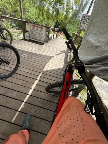 A reviewer's point-of-view wearing the vented, orange Coffindodger DC Park Pants while resting on a bike trail.