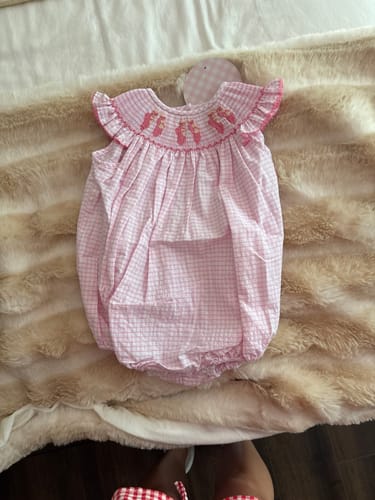 Reviewer's pink smocked Ballet Bubble outfit laid out flat, highlighting the detailed ballet slipper embroidery.