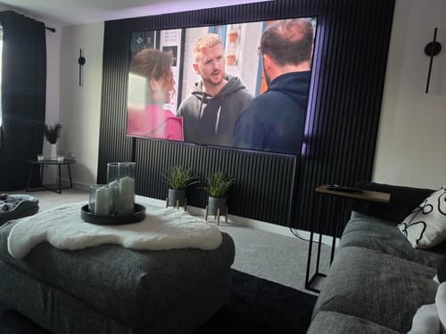 Reviewer's living room with black Acoustic Slatted Wall Panels installed as a modern feature wall behind a television.