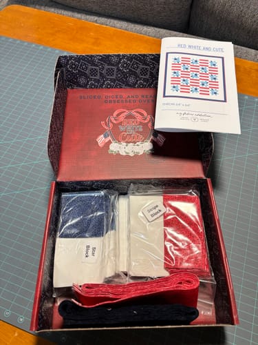 Customer's Red, White, and Cute Quilt Kit opened, showing precut fabric pieces and the pattern booklet inside.