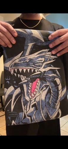 Customer holding up the black Yu-Gi-Oh!® Sweats, showing the large Blue-Eyes White Dragon graphic on the leg.