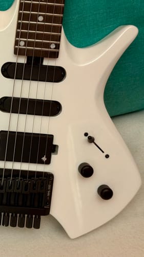 Rezensent zeigt eine Nahaufnahme seiner weißen Donner HLX-500 Headless E-Gitarre.