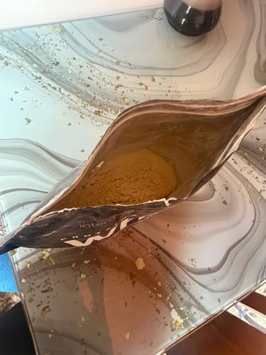 Cliente muestra el interior de la bolsa casi vacía de Proteína Whey en polvo sobre una mesa.