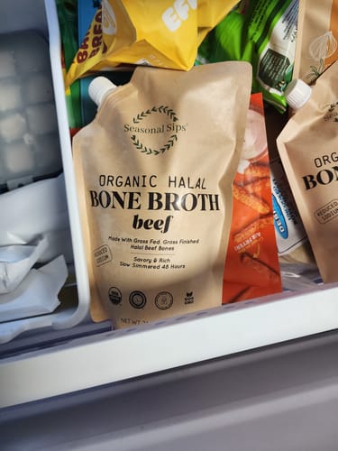 Customer's pouch of Organic Halal Beef Broth sitting inside a freezer drawer among other frozen goods.