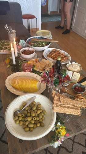 Anmelders grønne lysestake med tente lys på et festlig dekket bord med masse mat.
