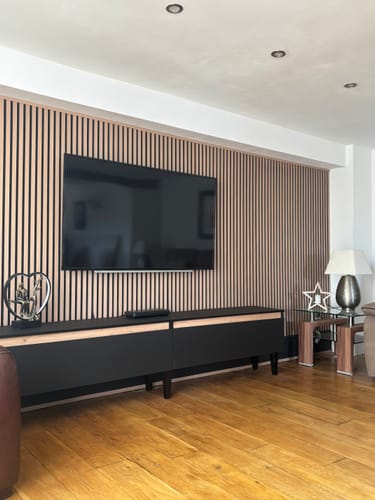A reviewer's living room showing the acoustic slatted wall panels installed as a stylish feature wall behind a mounted television.