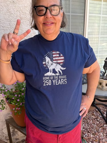 Reviewer smiling while wearing the navy blue Brave Howl - Premium t-shirt, showing off the patriotic wolf graphic.