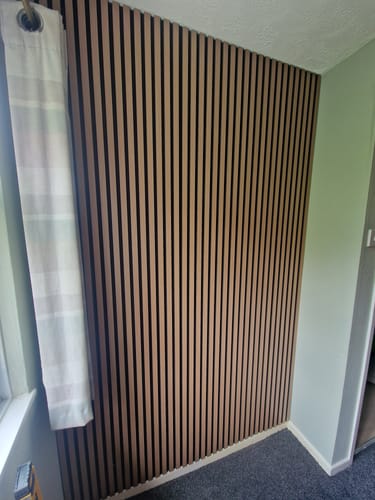 Customer's light wood acoustic slatted wall panels installed vertically as a feature wall in a room.