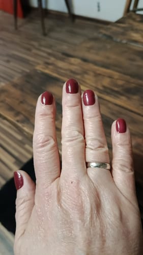 Rezensentenhand, die die glänzenden UV-Gel-Nagelfolien in der Farbe Rosé Chrome auf kurzen, ovalen Nägeln zeigt.