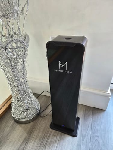 Customer's black TowerMax scent diffuser standing on a light wood floor in their large, open-plan home.