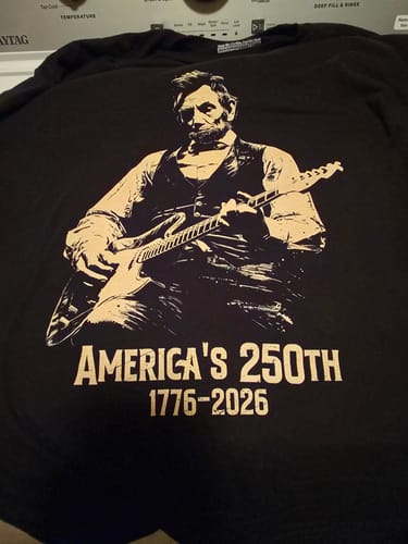 Customer's black Lincoln 250 T-shirt with a graphic of Abraham Lincoln playing a guitar over 'America's 250th 1776-2026'.