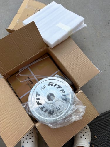 Customer unboxing a shiny silver RitFit Olympic plate from its shipping box.