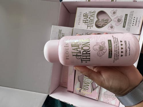 Customer holding the pink bottle of Hair to the Throne conditioner from the set.