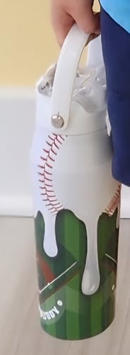 Customer holding a Bottle Buddy with a white strap and a melting baseball graphic over a green field design.