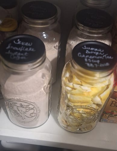 Reviewer's Chalkboard Top Mason Jar Lids with handwritten labels on several glass jars in a pantry.
