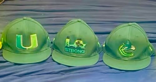 Reviewer's three custom green baseball caps arranged side-by-side, each featuring a unique embroidered logo.