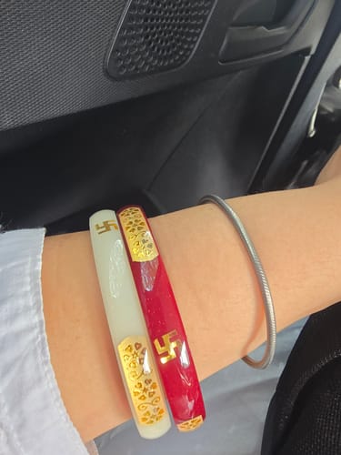 Reviewer's wrist wearing a white and a red Shweta Shree Shakha bangle, both with gold-plated details.