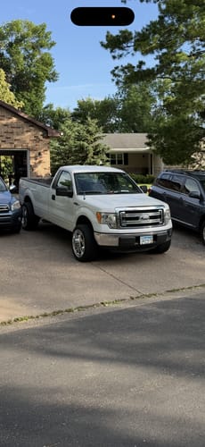 Customer's white Ford F150 in a driveway after installing the front leveling lift kit.