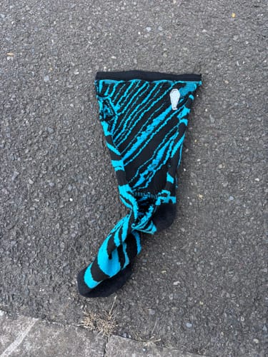 Customer's black and blue Compression Shred Sock with a jagged pattern lying on the asphalt.