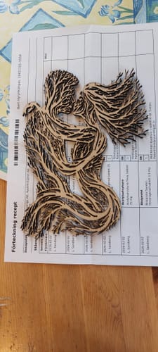 Customer's intricate laser-cut wood art of two tree-like figures embracing, a result of a project using the air purifier.