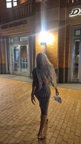 Rear view of a reviewer walking in the Naked Print Capri Legging and matching top at night.