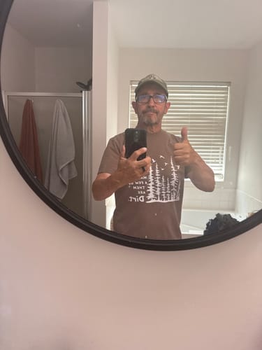 Reviewer in a mirror selfie wearing the brown Paths In Life T-shirt and giving a thumbs-up.