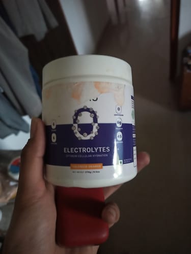 Customer holding a white tub of OSMO Electrolyte Hydration Blend in Valencia Orange.