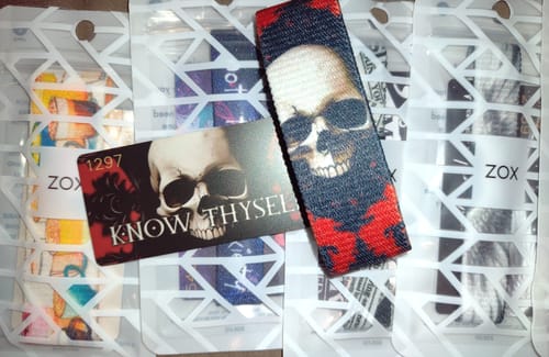 Customer's Know Thyself Bracelet with a skull design and its matching card, shown with other packaged bracelets from their order.