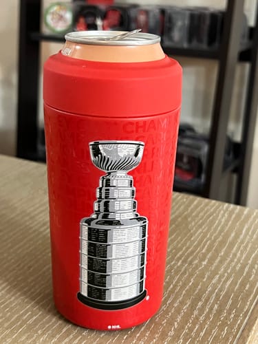 Customer's red Universal Buddy can cooler with a large Stanley Cup trophy graphic, holding a can on a table.