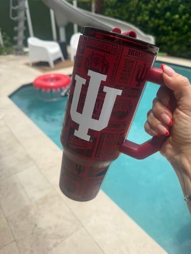 Customer holding a red Indiana Hoosiers Thicc Buddy tumbler by a pool, showing its large handle and IU logo.
