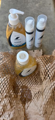 Customer's Sereni Krém bottle that arrived without a pump, showing the spilled product on the packing paper.