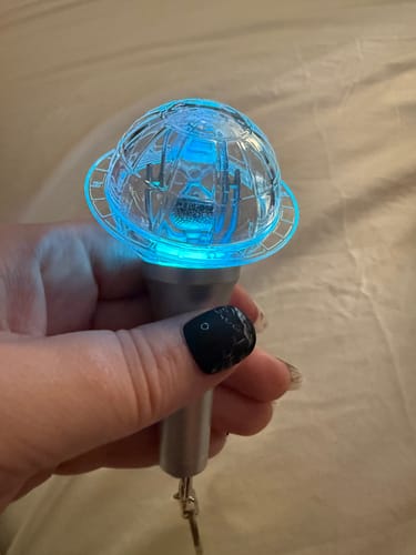 Customer holding the ATEEZ light stick keyring, lit up with a bright blue light.