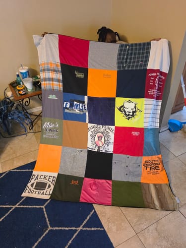Customer holding a large Project Repat T-Shirt Quilt made from a loved one's shirts as a keepsake.