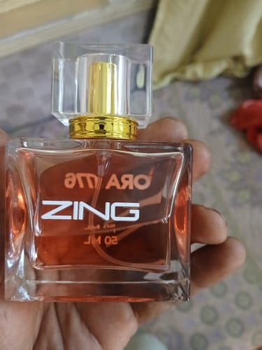 Customer holding a square glass bottle of amber-colored perfume with a gold cap.