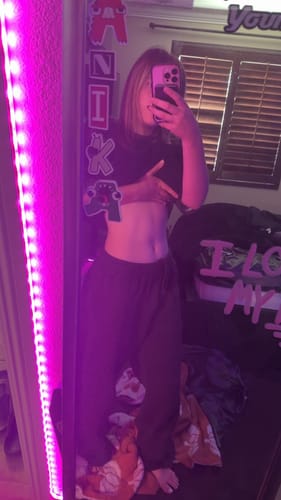 Reviewer lifting their black Oversized Baseball Tee while taking a selfie in a mirror.