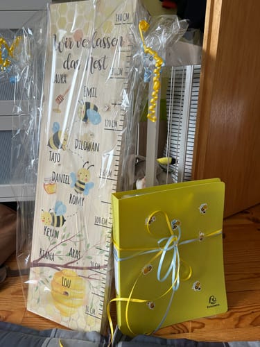 Kunde zeigt die personalisierte Messlatte aus Holz mit Bienenmotiv, die als Geschenk verpackt ist.