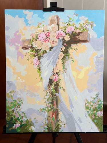 Customer's completed Floral Cross paint by numbers artwork of a cross with flowers, shown on an easel.