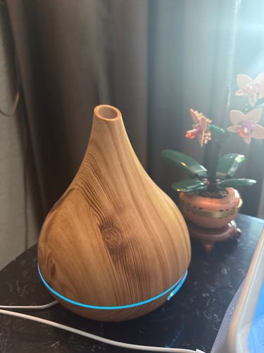 De licht houten Unity Aroma Diffuser van een recensent, werkend met een blauwe LED-gloed op een tafel.