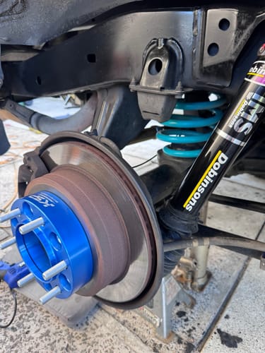 Customer's blue hubcentric wheel spacer installed on a vehicle's hub assembly, with the wheel removed for installation.