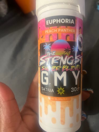Customer holding a jar of The Strongest GMY gummies, showing the colorful Peach Panther Sativa flavor label.