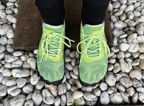 Reviewer wearing bright green Smart Ⅰ Pro - Barefoot Shoes, viewed from above while standing on white rocks.