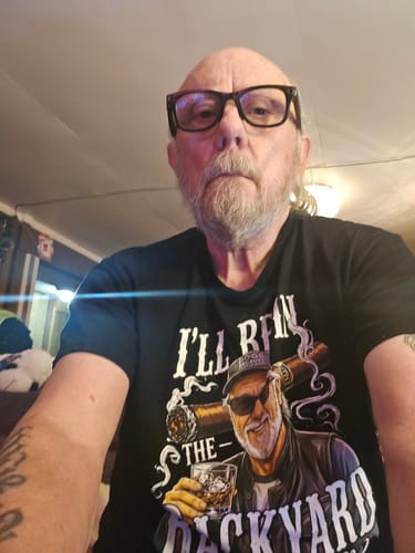 Customer taking a selfie while wearing the black 'I'll Be In The Backyard' funny t-shirt.
