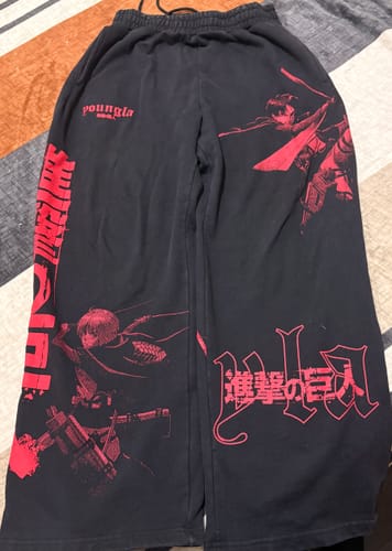 Customer's black AOT© x YLA Baggy Joggers laid out, showing the red Attack on Titan character graphics on the legs.